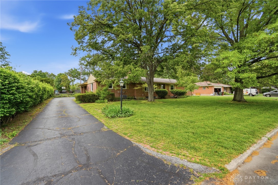 6119 Flemington Road Dayton, OH 45459 - Photo 69 of 76 Mature trees frame this charming brick residence with a paved driveway and lush lawn.
