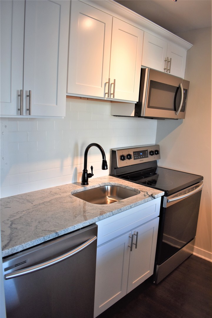 6166 North Sheridan Road, Unit 10D Chicago, IL 60660 - Photo 7 of 23 a kitchen with granite countertop a sink a stove and microwave
