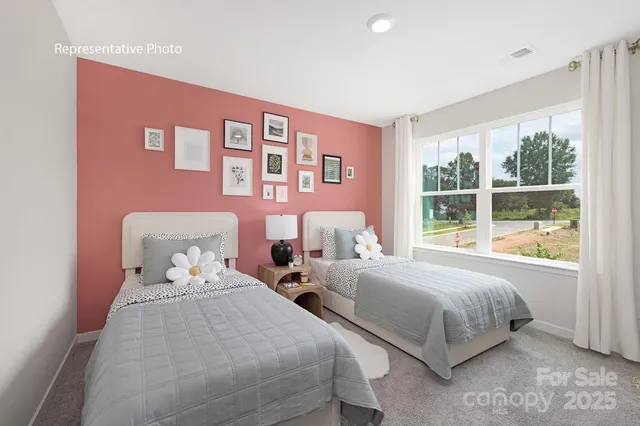 a bedroom with two beds and next to a window