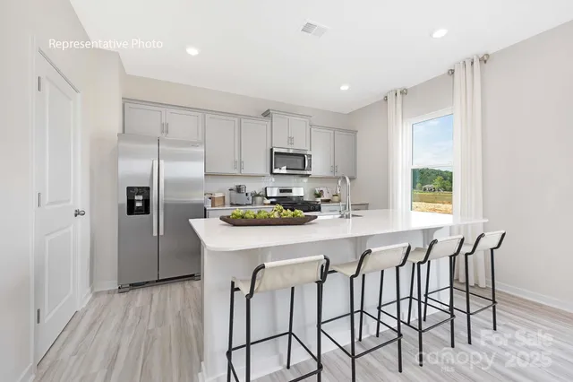a kitchen with stainless steel appliances granite countertop a table chairs refrigerator and microwave