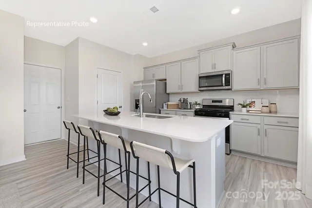 a kitchen with stainless steel appliances a white table chairs refrigerator microwave and cabinets