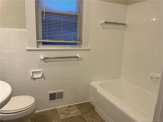 a white toilet sitting next to a bath tub