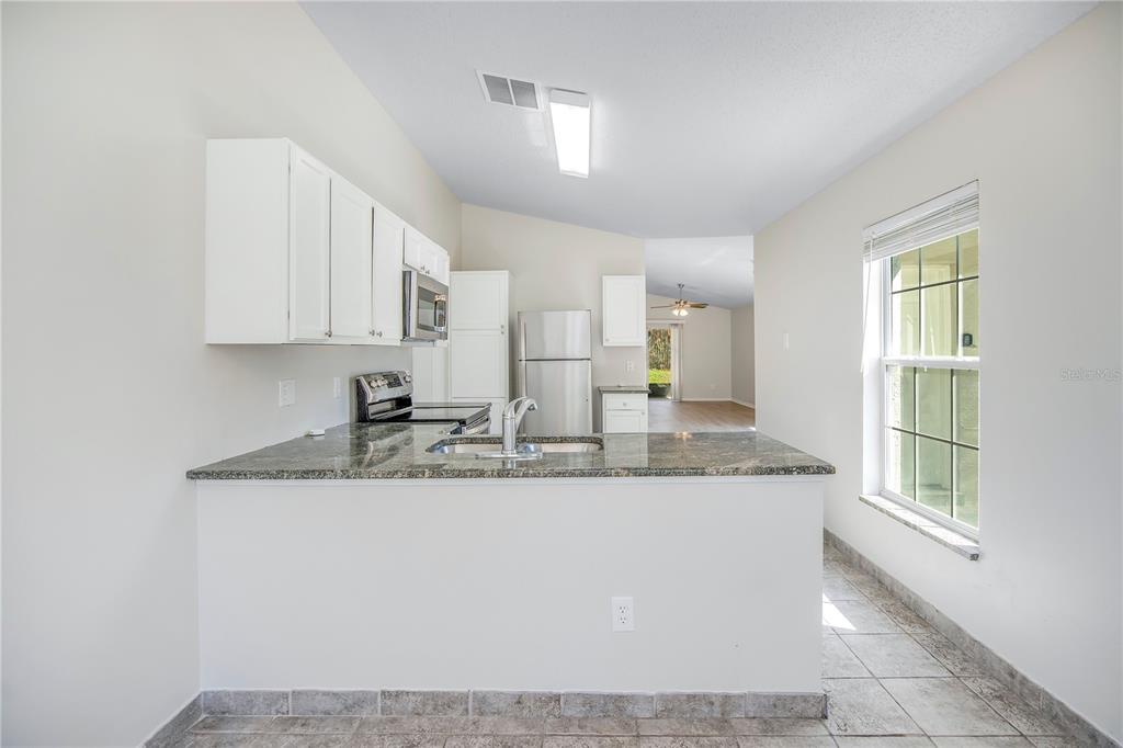1537 Rivers Edge Drive Orlando, FL 32825 - Photo 11 of 30 a kitchen with kitchen island granite countertop a sink window and cabinets