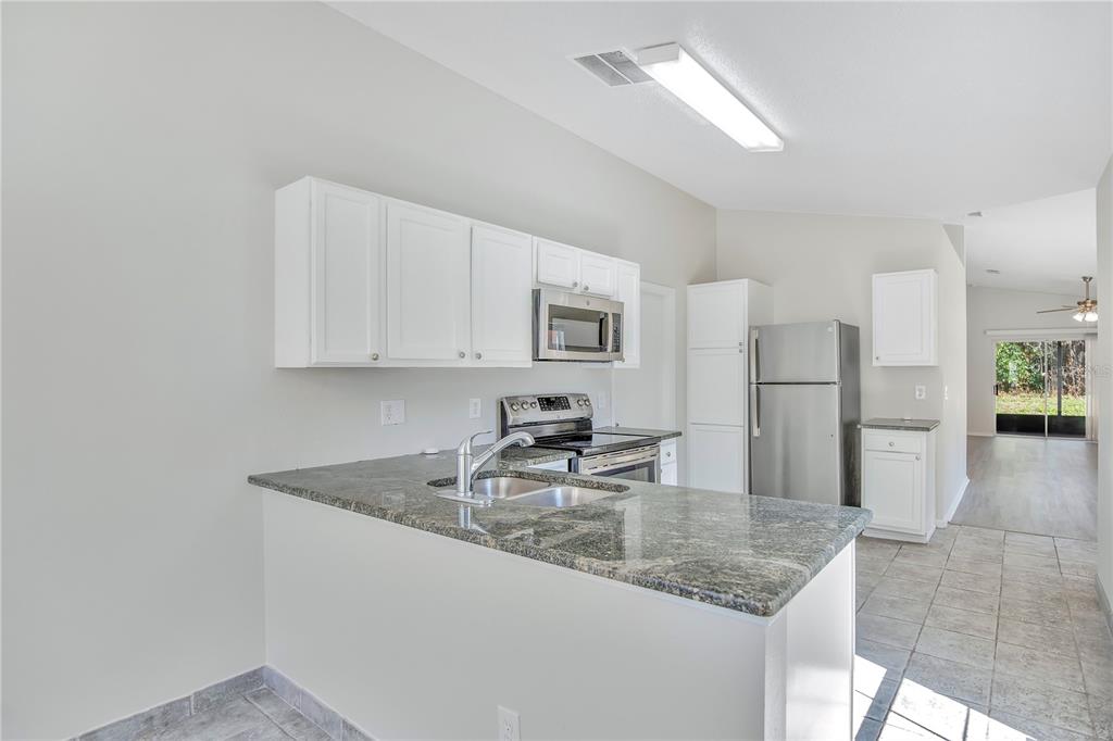 1537 Rivers Edge Drive Orlando, FL 32825 - Photo 12 of 30 a kitchen with stainless steel appliances granite countertop a sink refrigerator and cabinets