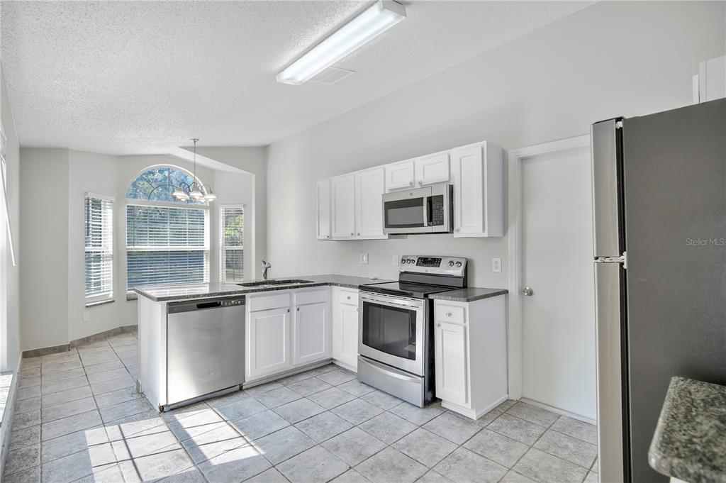 1537 Rivers Edge Drive Orlando, FL 32825 - Photo 9 of 30 a kitchen with stainless steel appliances granite countertop a stove a sink and a refrigerator