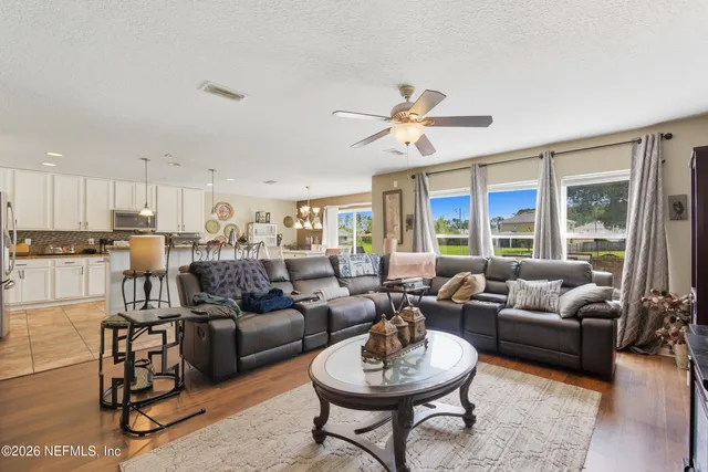 a kitchen with stainless steel appliances granite countertop a stove a refrigerator a kitchen island a stove and white cabinets with wooden floor