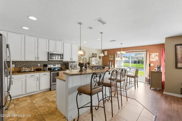 a kitchen with stainless steel appliances kitchen island granite countertop a refrigerator a stove a sink dishwasher with a dining table and chairs