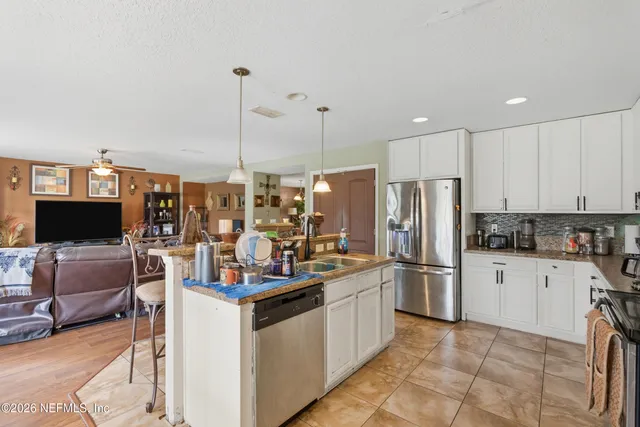 a kitchen with stainless steel appliances kitchen island granite countertop a sink stove and refrigerator