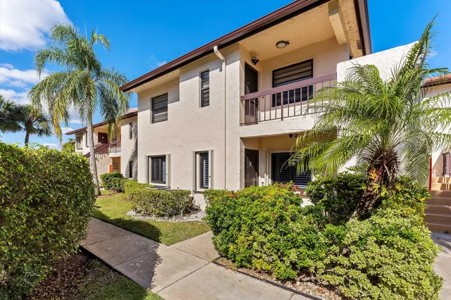 a front view of a multi story residential apartment building with yard and entryway