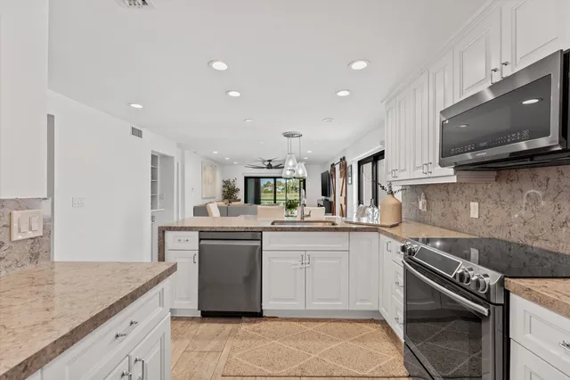 a kitchen with stainless steel appliances granite countertop a stove top oven a sink dishwasher a dining table and chairs with wooden floor