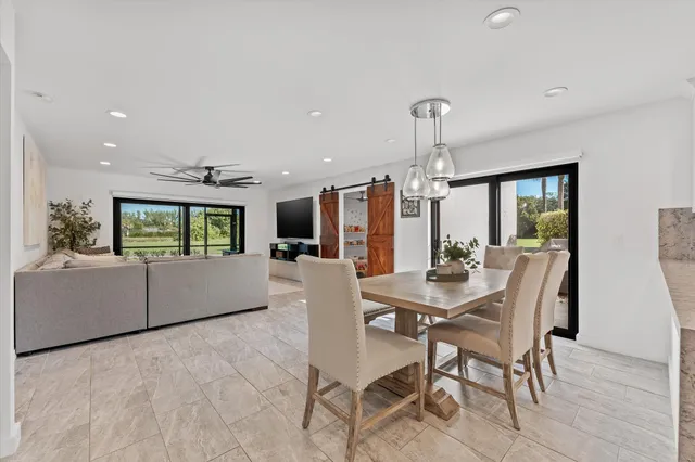 a living room with furniture a large window with stainless steel appliances kitchen island granite countertop furniture and a rug
