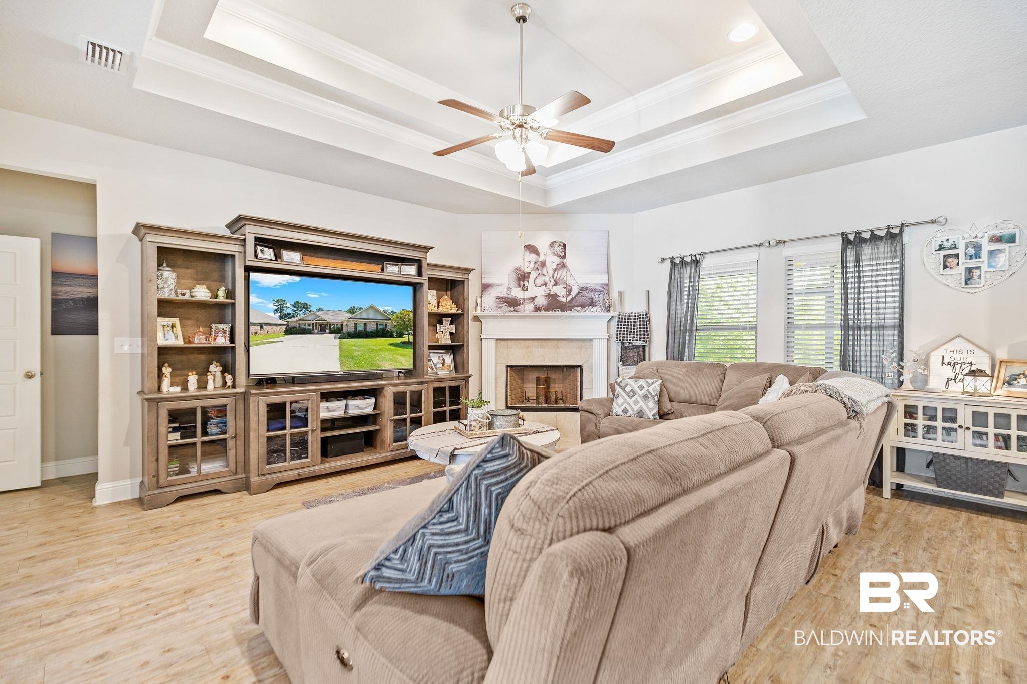 31402 Hoot Owl Road Daphne, AL 36527 - Photo 6 of 43 Living room featuring a fireplace, light hardwood / wood-style floors, ceiling fan, a raised ceiling, and ornamental molding