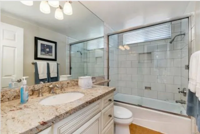 a bathroom with a granite countertop sink a toilet and shower