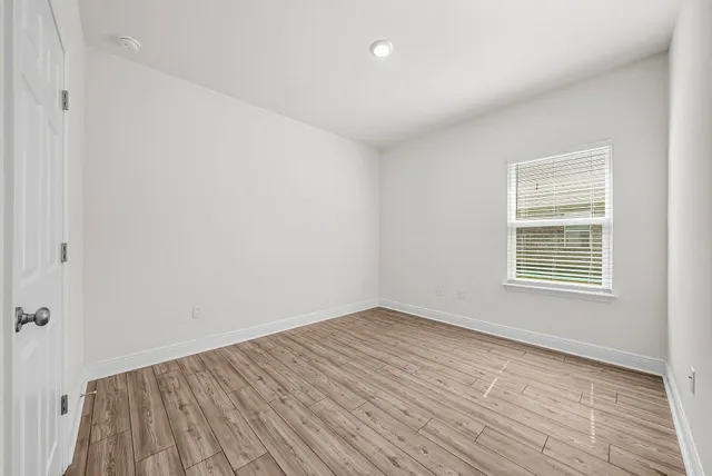 a view of an empty room with wooden floor and a window