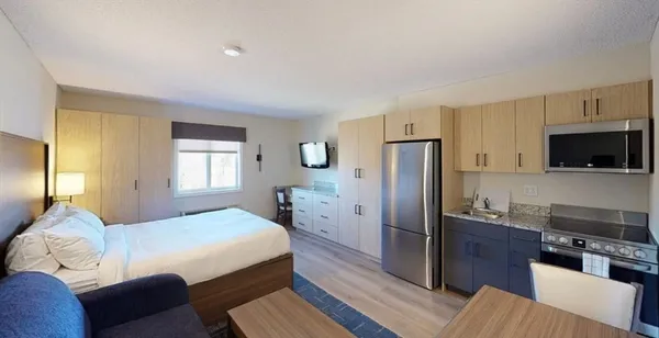 a bedroom with a bed a couch and a flat screen tv