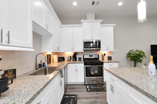 a kitchen with granite countertop a sink a counter space appliances and cabinets