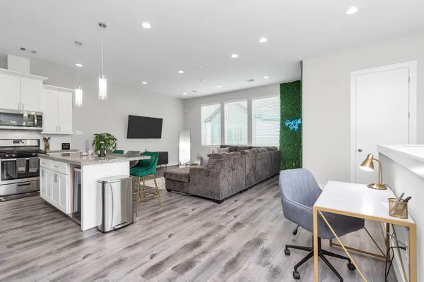 a living room with furniture a flat screen tv and kitchen view