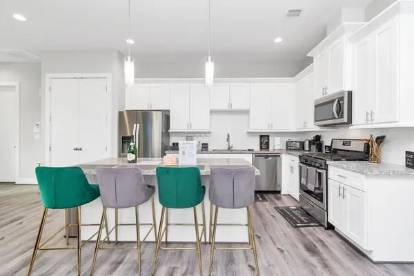 a kitchen with stainless steel appliances a table chairs refrigerator and a stove top oven