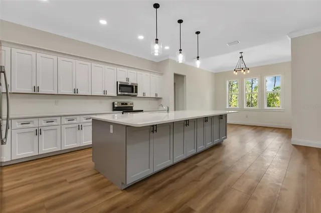 a kitchen with stainless steel appliances granite countertop a stove a sink dishwasher a refrigerator and a dining table with wooden floor