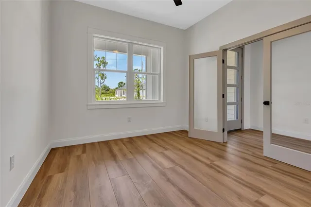 a view of an empty room with wooden floor and a window