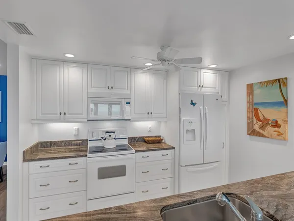 a kitchen with granite countertop white cabinets and stainless steel appliances
