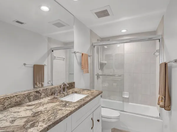 a bathroom with a granite countertop sink toilet and shower