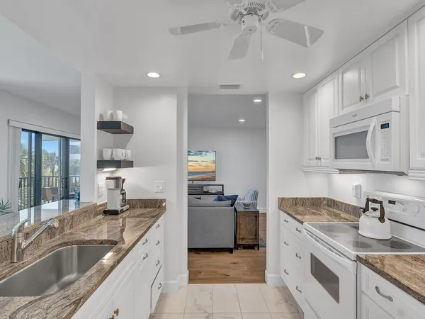 a kitchen with granite countertop a sink stove and cabinets