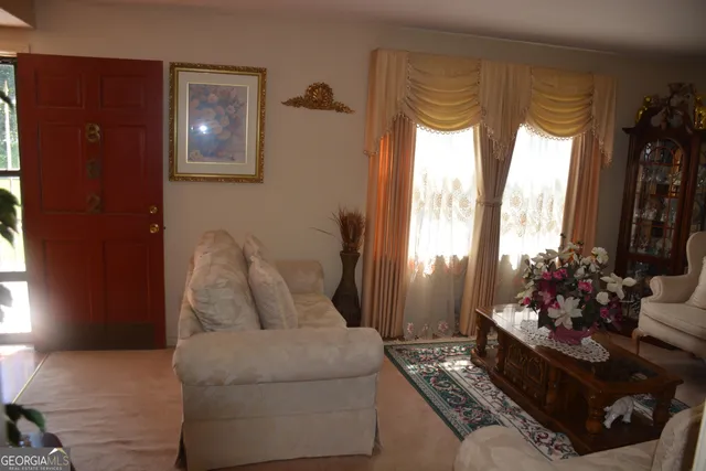 a living room with furniture large window and wooden floor