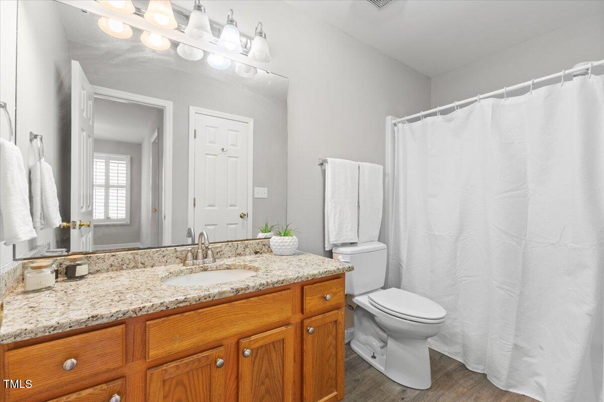 723 Renshaw Court Cary, NC 27518 - Photo 26 of 34 a bathroom with a granite countertop sink a toilet and a mirror