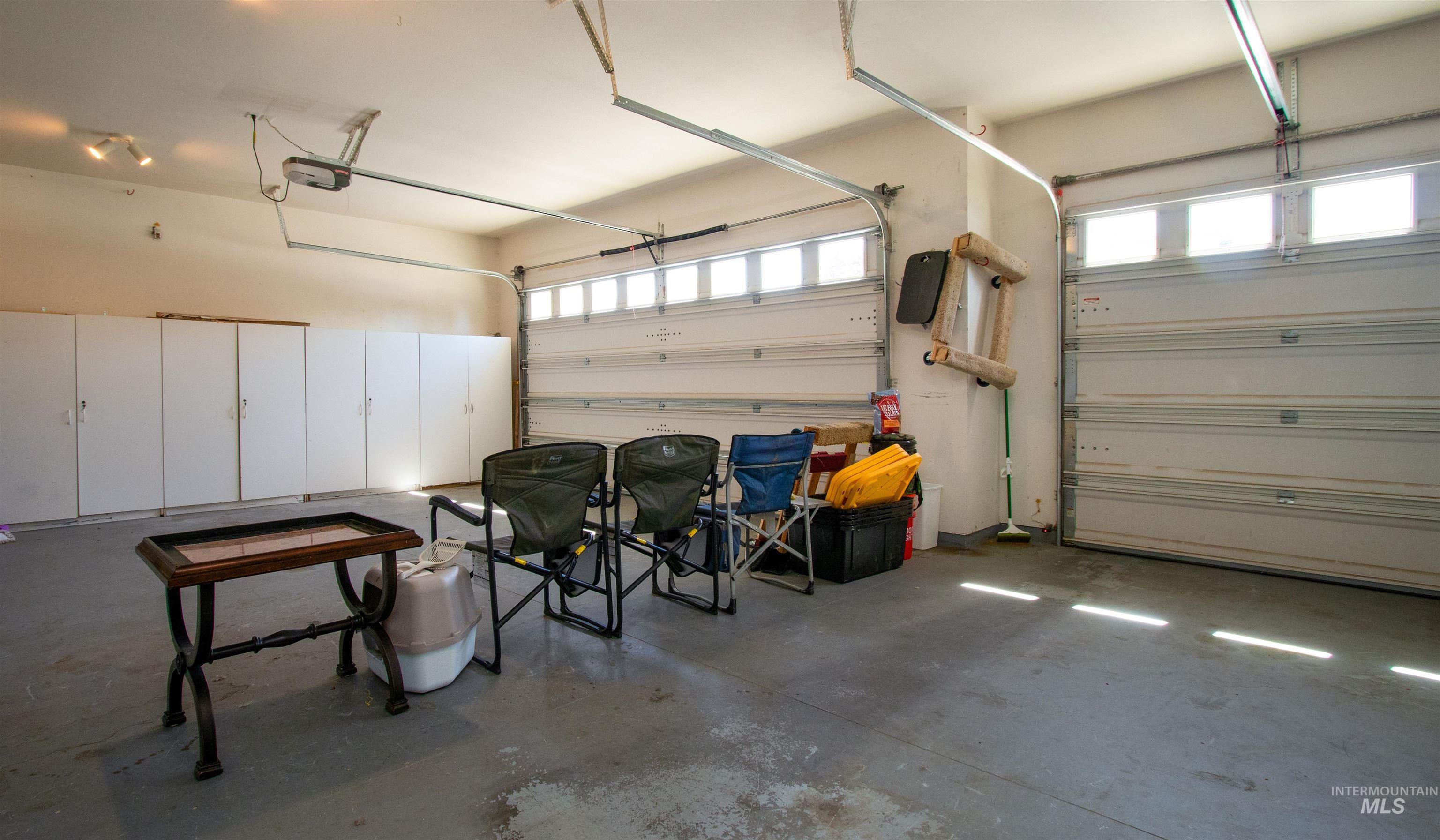 892 South Capitola Way Boise, ID 83712 - Photo 23 of 34 Spacious garage featuring two overhead doors with transom windows, extensive built-in cabinetry, durable concrete flooring, and track lighting