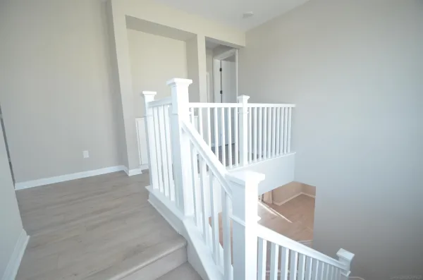 a view of staircase with railing and white walls