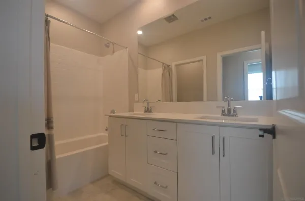 a bathroom with a granite countertop sink a mirror a vanity and a bathtub