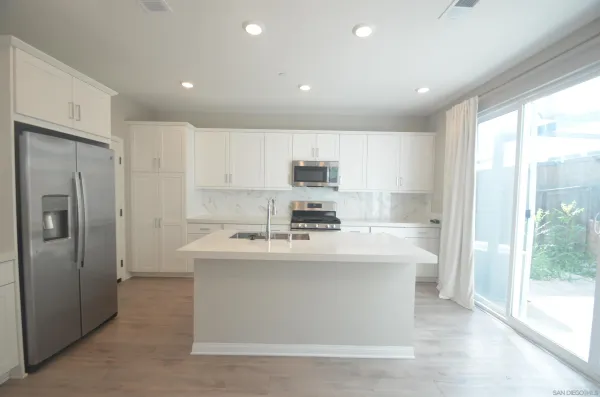 a view of a kitchen with kitchen island a sink stainless steel appliances and cabinets