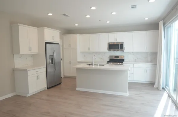 a kitchen with a refrigerator and white cabinets