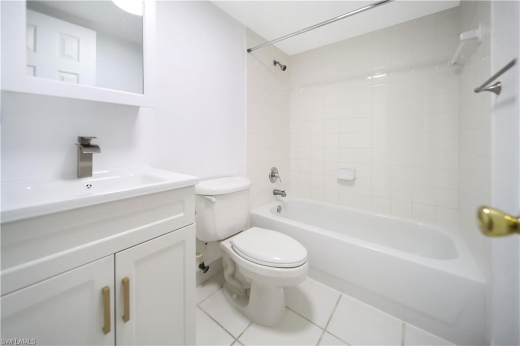 4621 Bayshore Drive, Unit Q4 Naples, FL 34112 - Photo 11 of 12 a white toilet sitting next to a bathroom sink and vanity