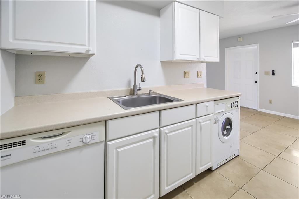 4621 Bayshore Drive, Unit Q4 Naples, FL 34112 - Photo 5 of 12 a kitchen with white cabinets and white appliances