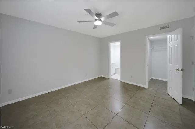 an empty room with closet and a ceiling fan