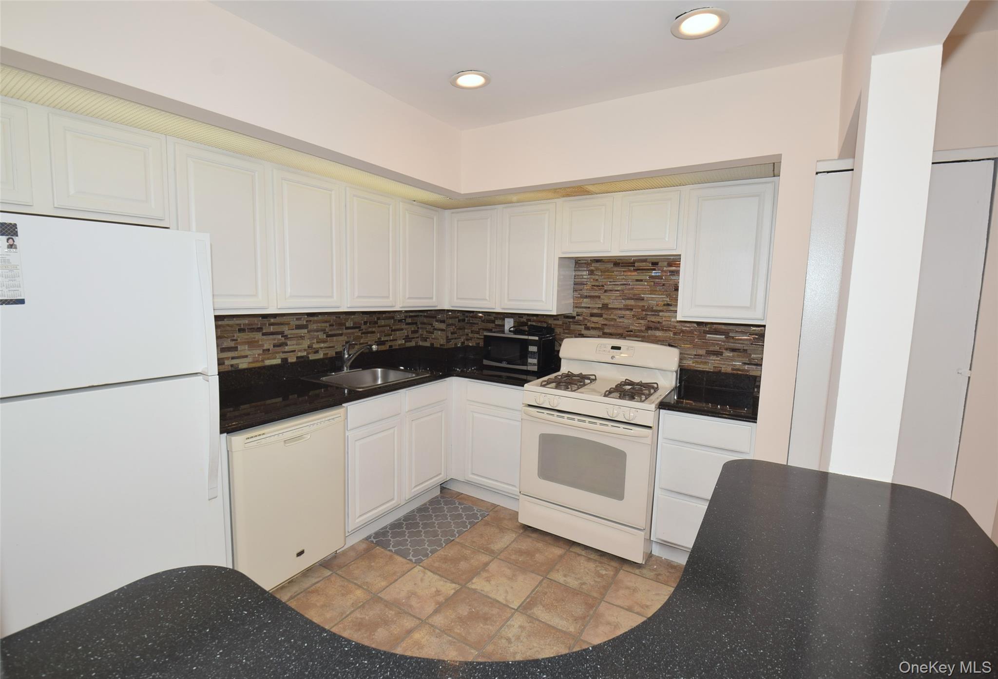 206-14 Emily Road, Unit 42L Queens, NY 11360 - Photo 4 of 14 a kitchen with a stove and white cabinets