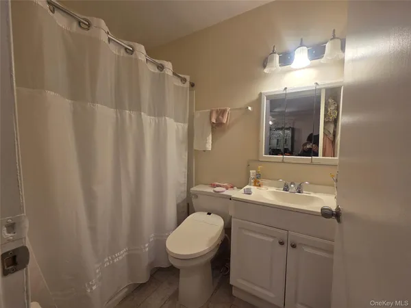 a bathroom with a sink a toilet a mirror a lamp and vanity