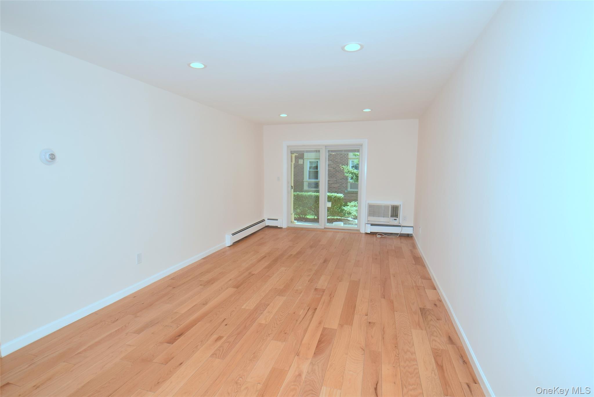 206-14 Emily Road, Unit 42L Queens, NY 11360 - Photo 7 of 14 a view of an empty room with wooden floor and a window