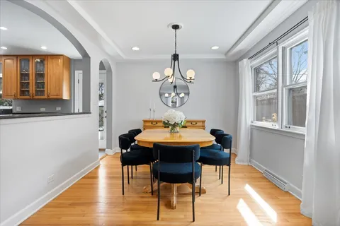 a dining room with chandelier and wooden floor