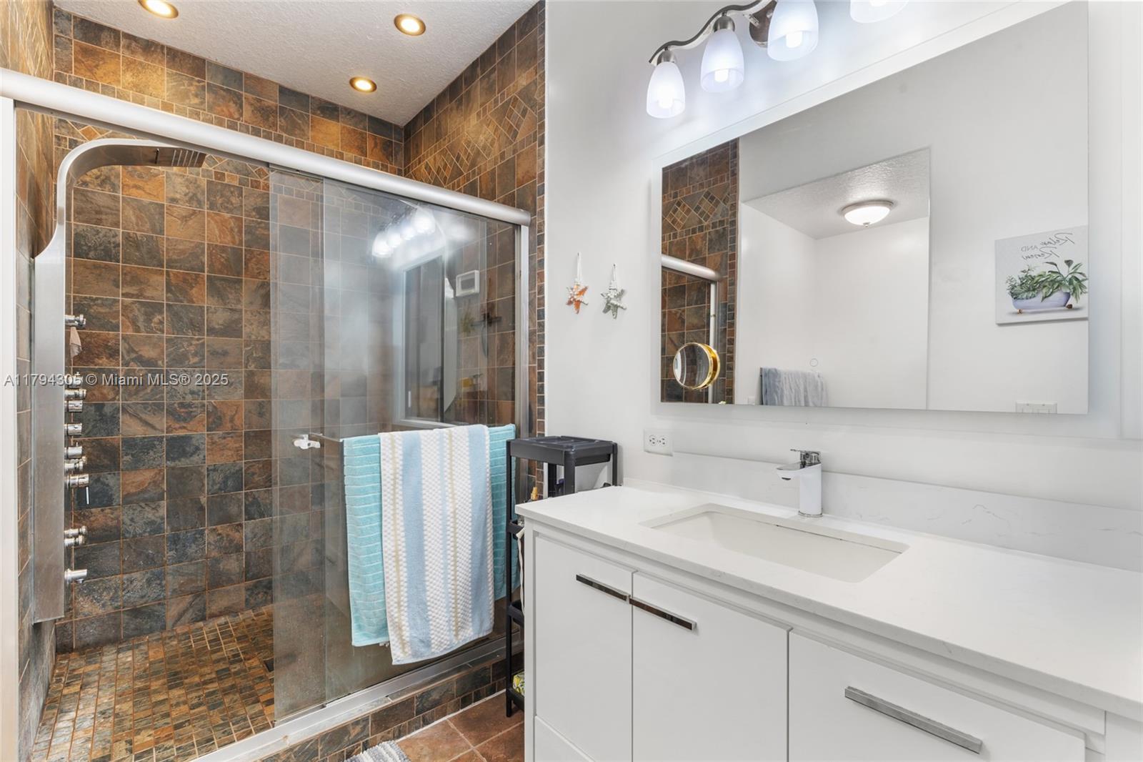 10012 Northwest 7th Street, Unit 107 Miami, FL 33172 - Photo 30 of 44 a bathroom with a double vanity sink mirror and shower