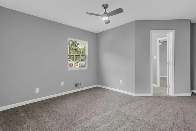 an empty room with fan and windows