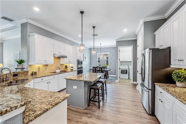 a kitchen with stainless steel appliances granite countertop wooden floor sink stove and refrigerator