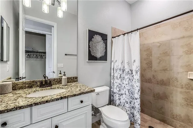 a bathroom with a granite countertop sink a toilet and shower