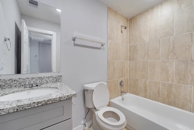 a bathroom with a granite countertop sink a toilet and bathtub