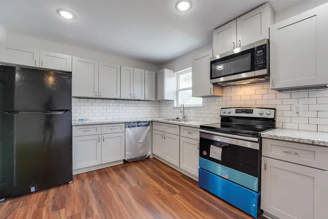 a kitchen with stainless steel appliances granite countertop a refrigerator stove a sink and dishwasher with wooden floor