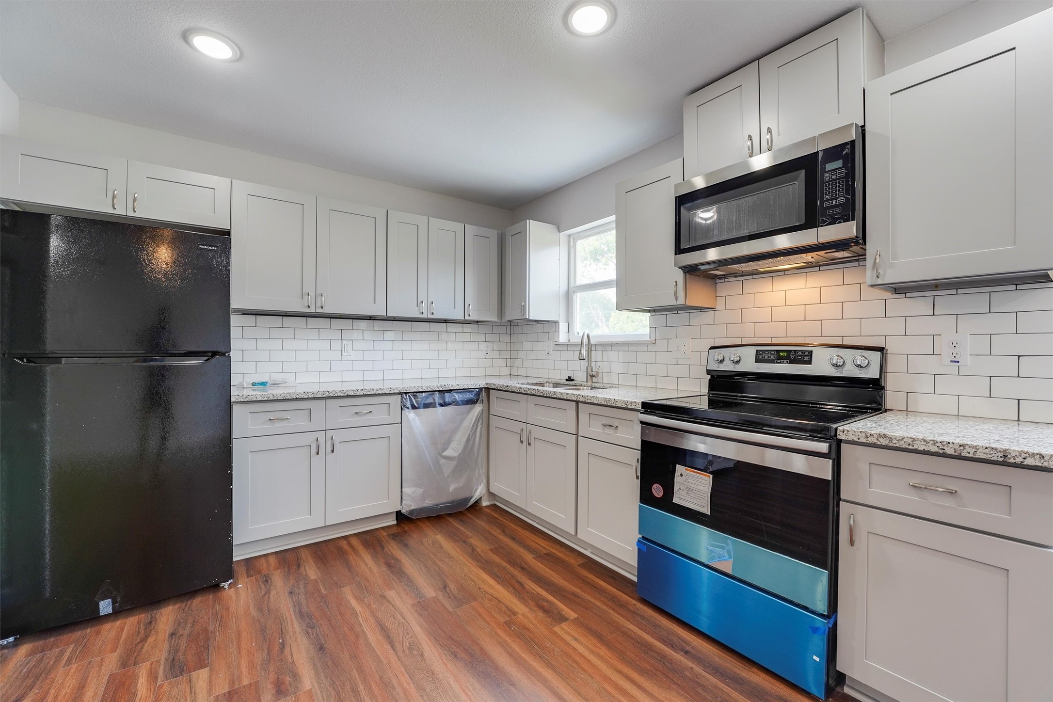 6716 Haight Street, Unit A Houston, TX 77028 - Photo 4 of 14 a kitchen with stainless steel appliances granite countertop a refrigerator stove a sink and dishwasher with wooden floor