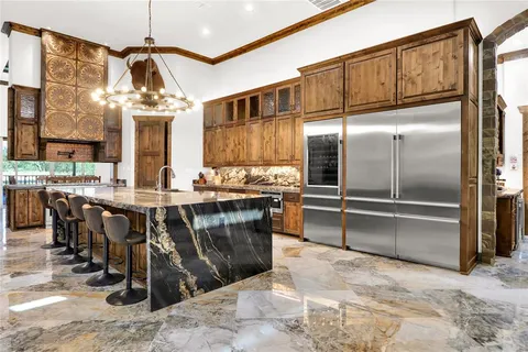 a kitchen with kitchen island granite countertop a refrigerator a stove a sink and a dining table with wooden floor