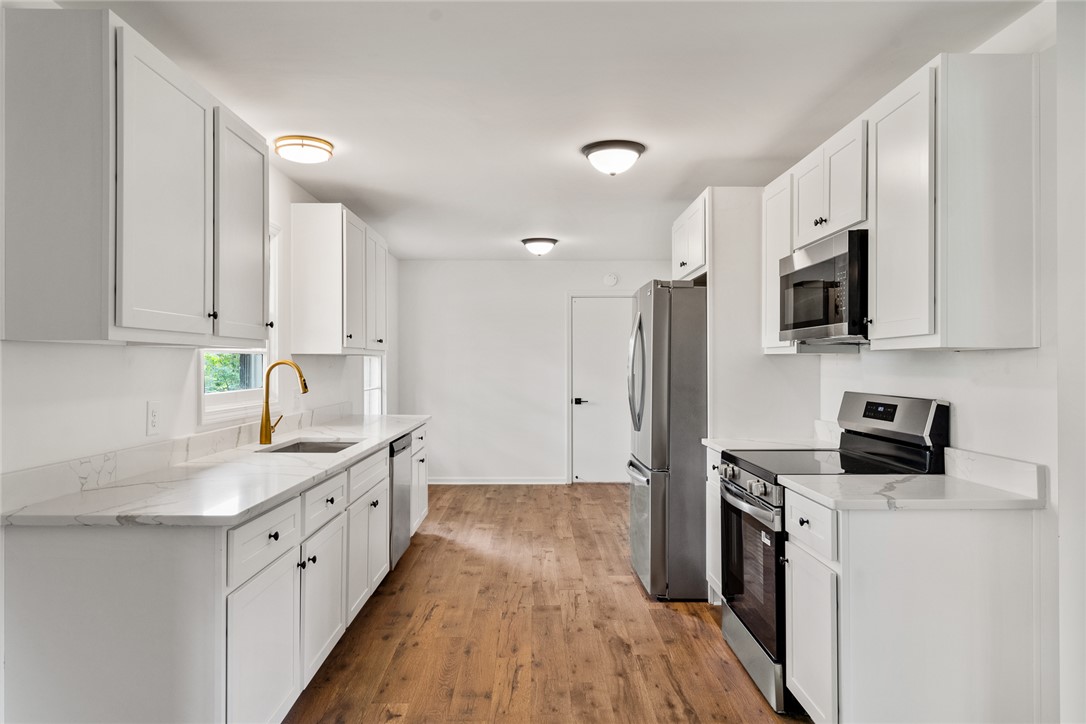 300 Vandiver Road Anderson, SC 29621 - Photo 9 of 30 A pristine culinary space awaits, featuring sleek white cabinetry and warm wood flooring.
